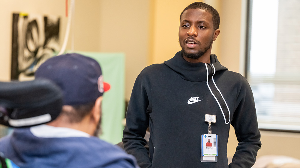 Peer liaison Daquarius Greene speaks to a patient at the Shepherd Center.